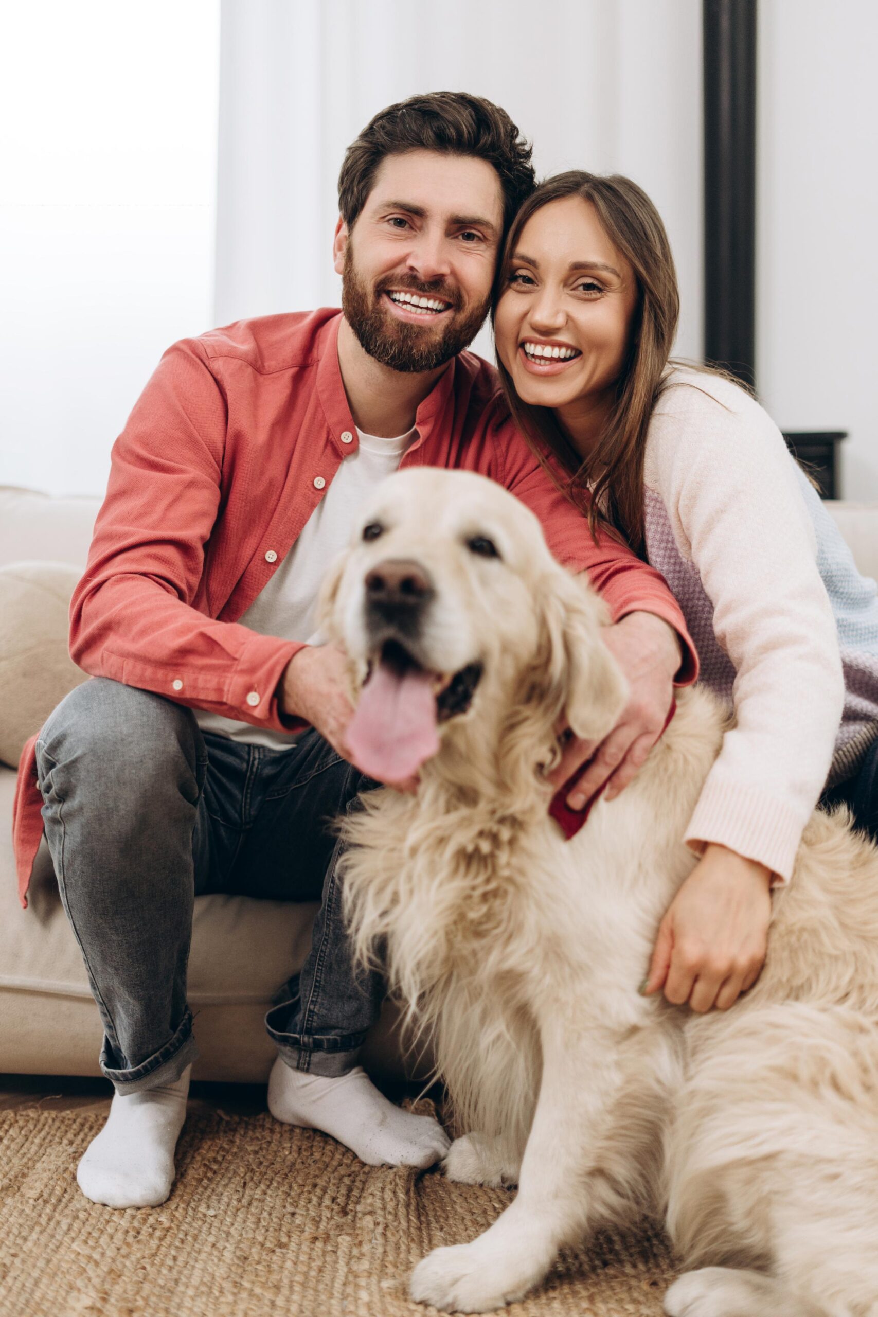 happy-couple-smiling-embracing-golden-retriever-home